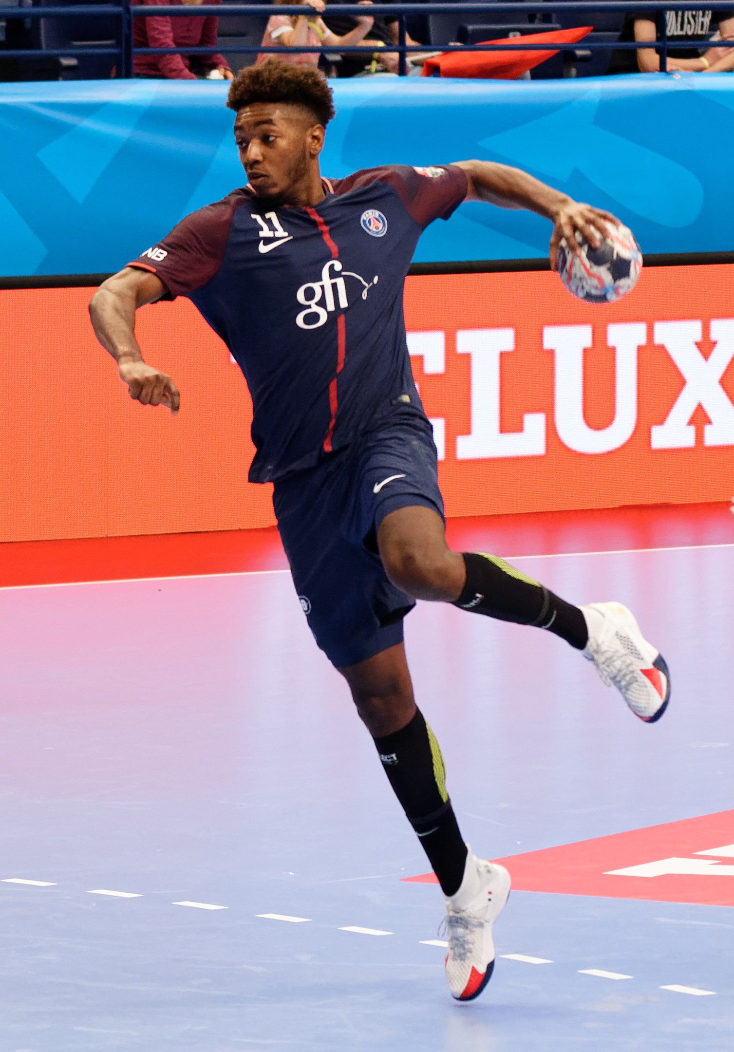 Mann in blauem Paris-Saint-Germain-Trikot hält einen Handball in einem Stadion während der Futsal-Weltmeisterschaft 2019, mit Zuschauern im Hintergrund.