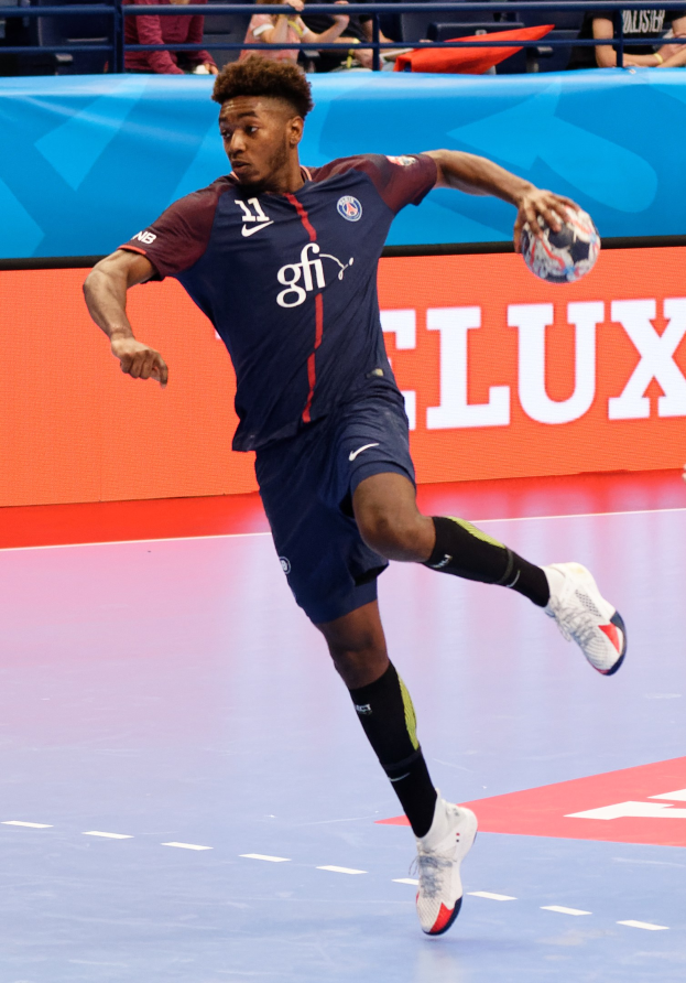 Mann in blauem Paris-Saint-Germain-Trikot hält einen Handball in einem Stadion während der Futsal-Weltmeisterschaft 2019, mit Zuschauern im Hintergrund.