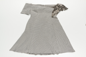 Ein schwarzes und weißes Knie-langes Kleid mit Pailletten, das eine taillierte Taille und einen weiten Rock hat, vor einem weißen Hintergrund.