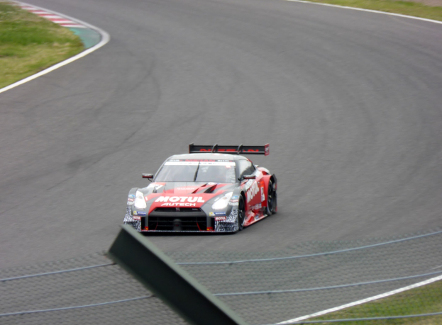 Ein Nissan GT-R Nismo GT3 Rennauto auf der Nürburgring 24 Stunden Strecke, mit grünem Gras auf beiden Seiten des Asphalts.
