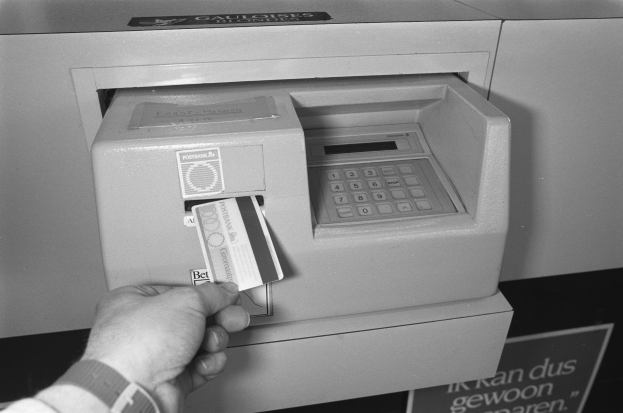 Eine Person, die eine Karte in einen Geldautomaten einführt, mit der Szene in Schwarz-Weiß.