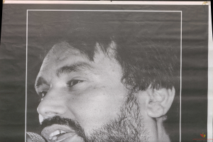 Ein Schwarz-Weiß-Foto eines bärtigen Mannes, der ein Mikrofon hält und mit geschlossenen Augen und leicht geöffnetem Mund singt.