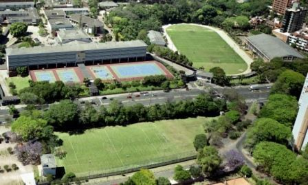 Luftaufnahme eines Fußballfeldes an der Universität Sydney, umgeben von Bäumen, Gebäuden und Fahrzeugen auf der Straße als Teil eines neuen Sportkomplexes.
