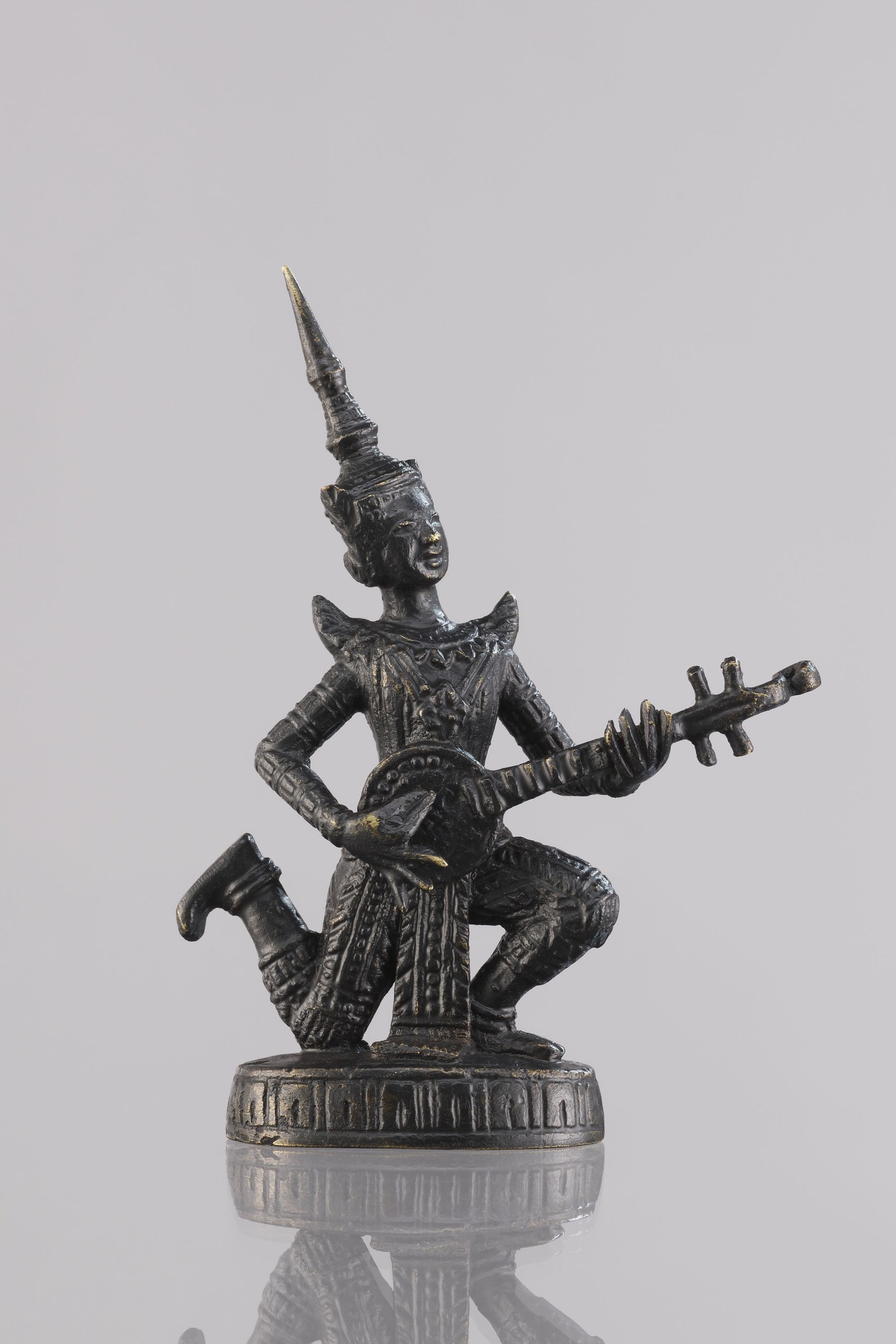 Bronzestatue eines Mannes mit einer Gitarre vor einem weißen Hintergrund.