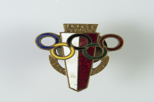 Ein Abzeichen mit einem weißen Hintergrund und einem rot, weiß und blauen Design mit den Olympischen Ringen und darauf geschriebenem Text.