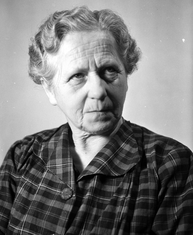 Ein altes Weib in einem Schwarz-Weiß-Foto mit faltigem Gesicht, zurückgekämmtem Haar, geschlossenen Augen und leicht geöffneten Lippen, das friedlich wirkt.