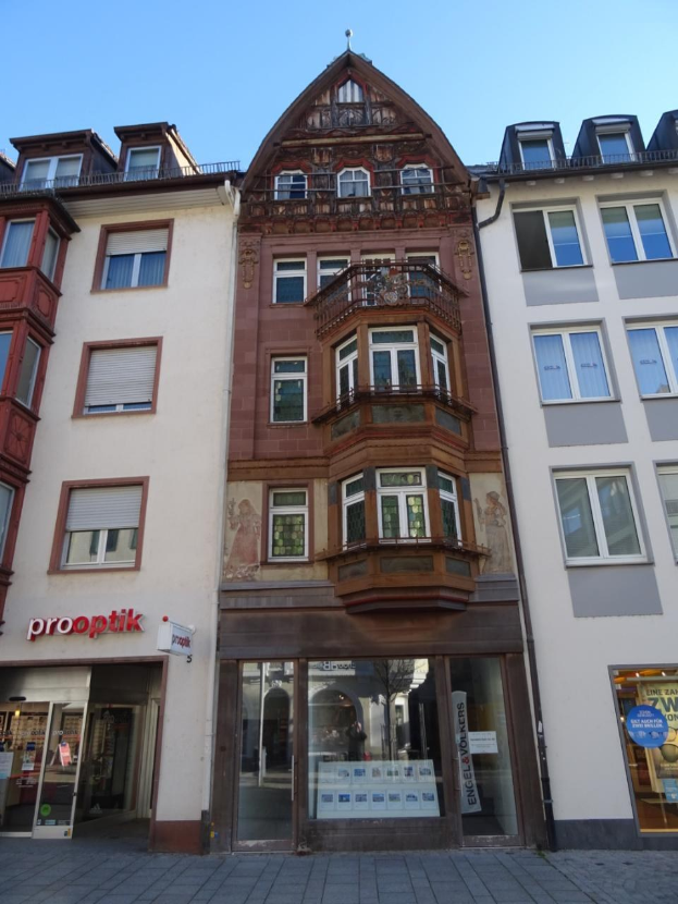 Ein gewerbliches Gebäude mit mehreren Fenstern zum Verkauf, das sich auf einer Straße in Heidelberg, Deutschland, unter einem klaren blauen Himmel befindet.