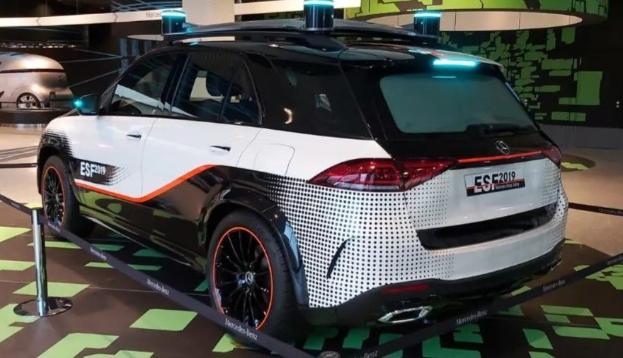 Mercedes-Benz E-Klasse Electric SUV auf der IAA in Frankfurt, umgeben von Absperrpollern mit Seilen und Lichtern, mit einem weiteren Fahrzeug und einer textbedeckten Wand im Hintergrund.