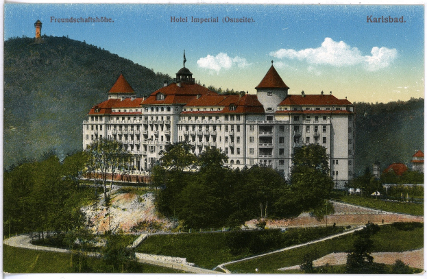 Alte Postkarte des Hotel Imperial in Karlsbad, Deutschland, zeigt ein großes Gebäude mit Fenstern umgeben von Bäumen, Pflanzen, einem Pfad, Hügeln und einem bewölkten Himmel.