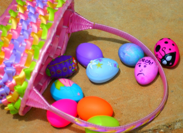 Ein Korb mit mehreren bunten Ostereiern, der an einer Wand hängt.