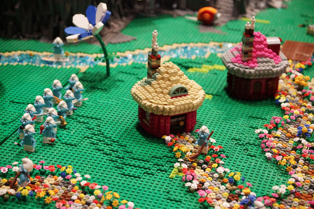 Ein Lego-Modell einer Kleinstadt mit Blumen, Spielzeugen, Häusern, Pflanzen und anderen Gegenständen vor einem leicht unscharfen Hintergrund.