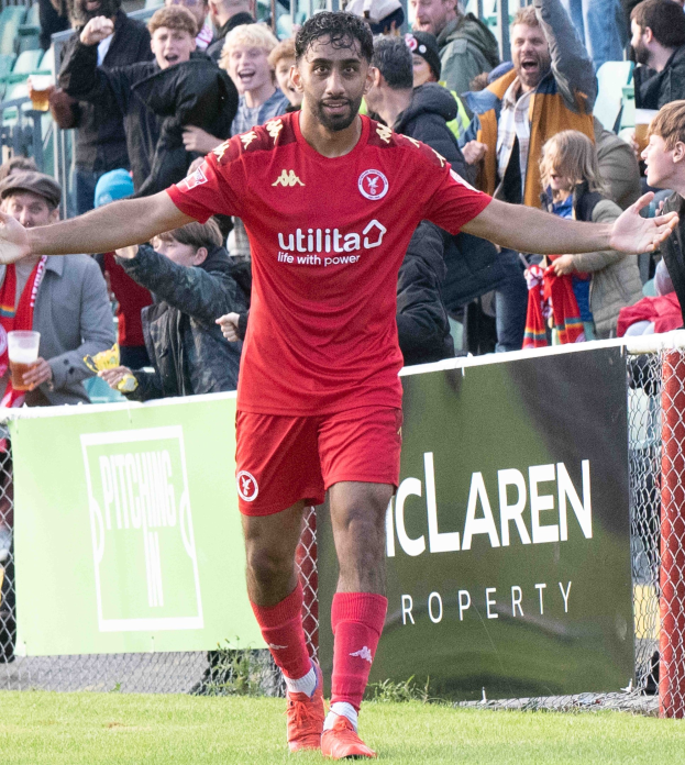 Ein Fußballspieler in roter Uniform rennt mit ausgebreiteten Armen auf einem Feld, umgeben von einer Menge, mit einem "Middlesbrough FC v Swansea City - Sky Bet Championship"-Banner im Hintergrund.