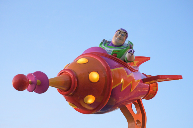 Buzz Lightyear aus Toy Story 4 fliegt in einem Spielzeug-Raumschiff im Disney's Hollywood Studios gegen einen hellblauen Himmel.