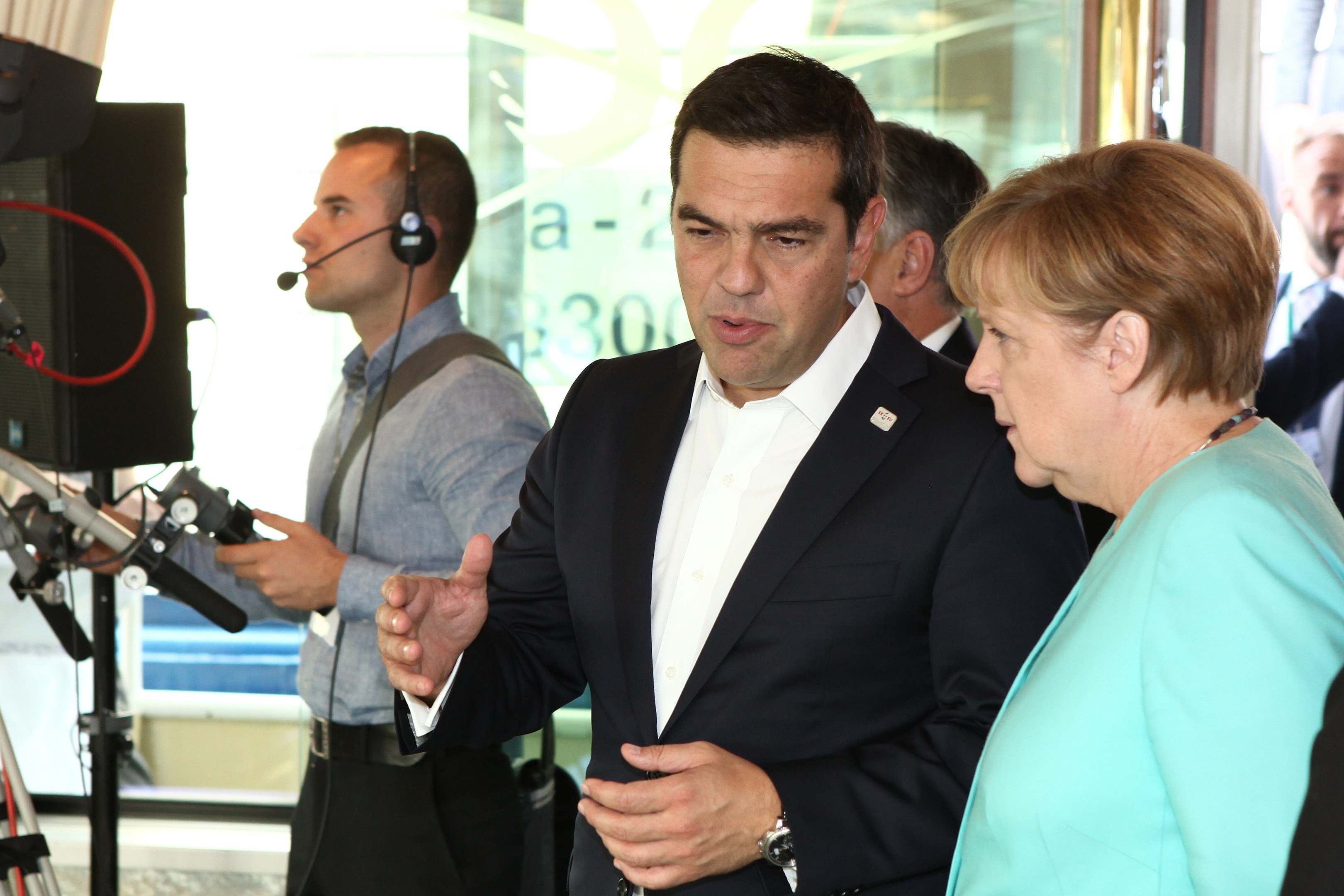Bundeskanzlerin Angela Merkel und Joachim Gauck vor einer Glaswand mit Vorhang, beide im Anzug und mit Mikrofonen.