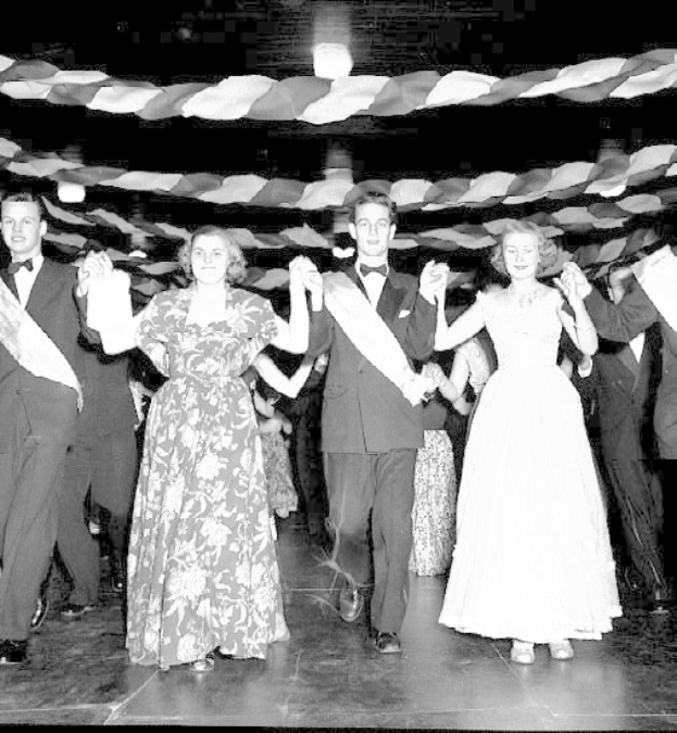 Schwarzes und weißes Bild einer Gruppe von Menschen in Abendgarderobe, die auf einem geschmückten Tanzboden tanzen.