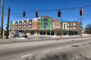 Stadtstraßenszene mit Ampeln, Strommasten, Kabeln, Verkehrskegeln, Fahrzeugen, Bäumen, Gebäuden und Himmel, mit einem Eckgebäude im Bau.