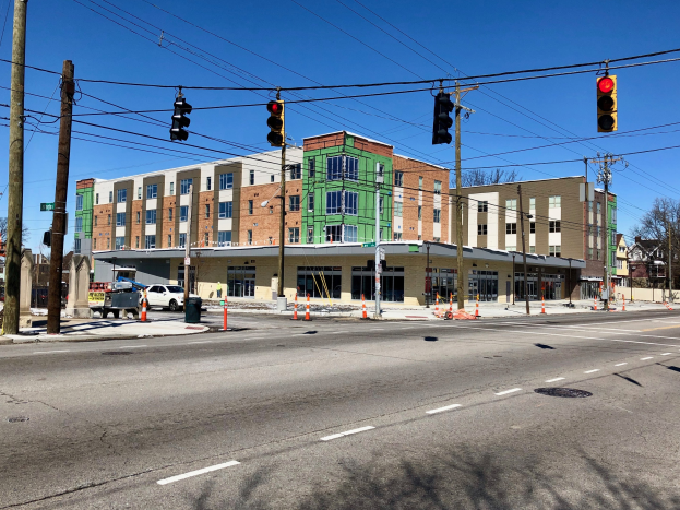 Stadtstraßenszene mit Ampeln, Strommasten, Kabeln, Verkehrskegeln, Fahrzeugen, Bäumen, Gebäuden und Himmel, mit einem Eckgebäude im Bau.