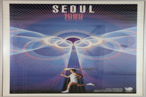 Eine Person, die mit den Olympischen Ringen im Hintergrund läuft, und die Wörter "Olympische Spiele" quer über einem Plakat für die Olympischen Spiele 1988 in Seoul, Südkorea, geschrieben.