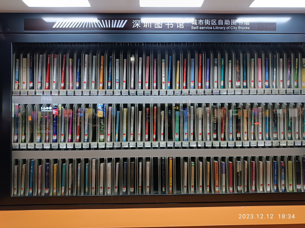 Eine gut beleuchtete Bibliothek mit hohen Bücherregalen voller Bücher, einer Tafel mit Text und einem Wasserzeichen unten.