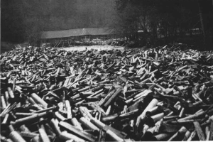 Ein Schwarz-Weiß-Foto eines großen Haufens von Kugeln im Vordergrund, mit einer Hütte und Bäumen im Hintergrund und dem Text "Weltkrieg II" unten.