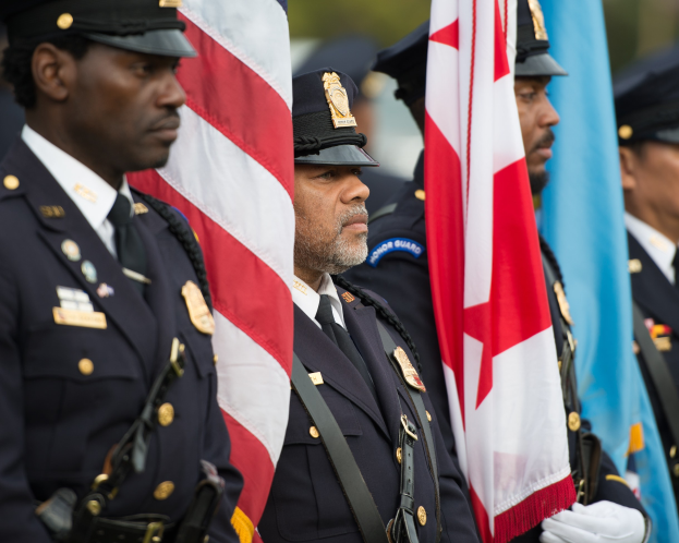Gruppe von Polizisten in Uniform, die zusammenstehen und Fahnen halten, mit einem unscharfen Hintergrund.