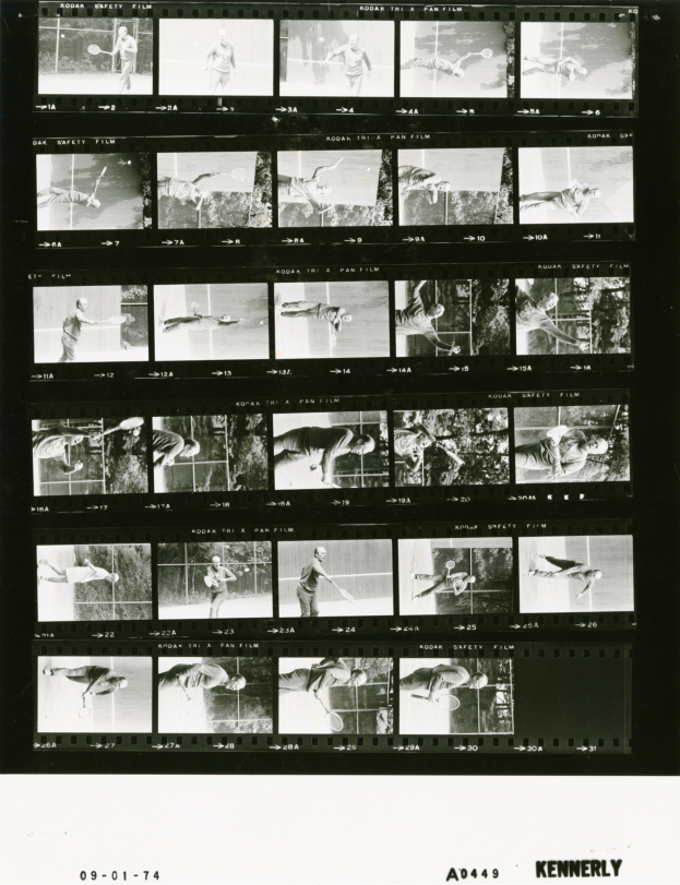 Schwarzes und weißes Foto eines Mannes in einem weißen Hemd und Shorts, der Tennis spielt und einen Schläger in der rechten Hand hält, mit einem Filmstreifen im Hintergrund und einem konzentrierten Gesichtsausdruck.